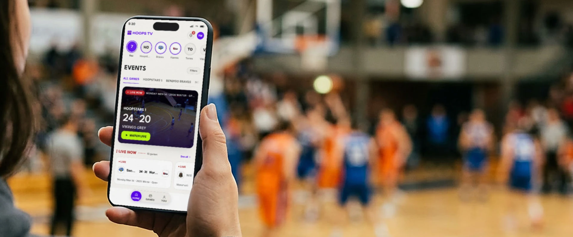 Basketball fan watching a HoopsTV game on a phone from courtside